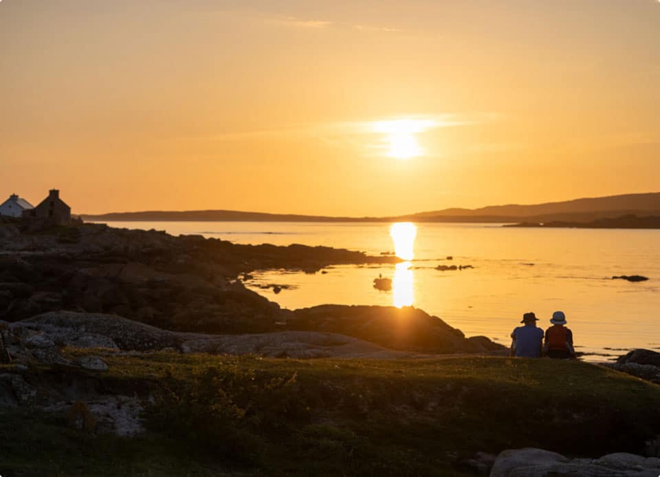 Two friends watching the sunset over a Connemara bay