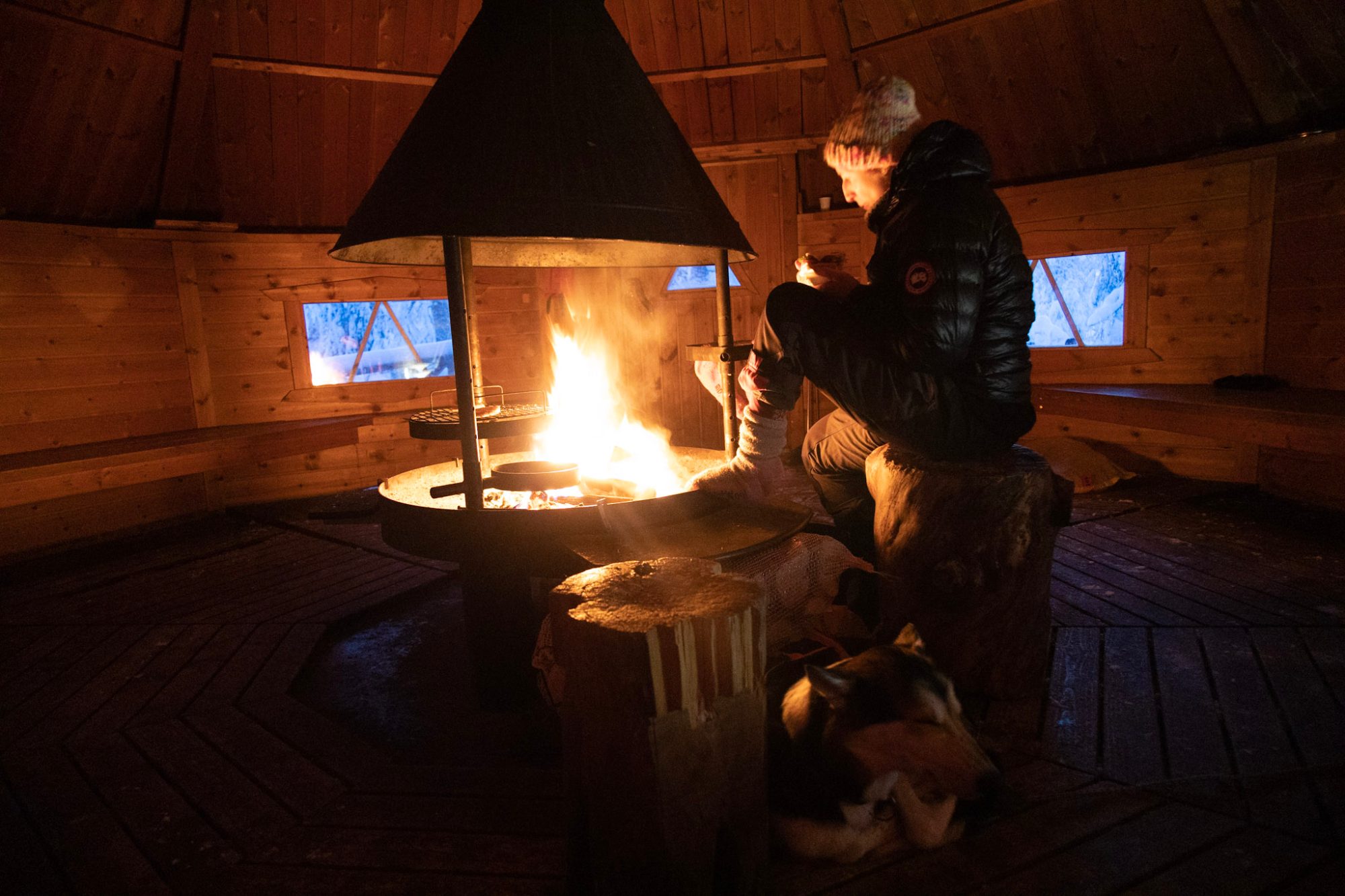 Warming up by the fire inside a wooden kota hut